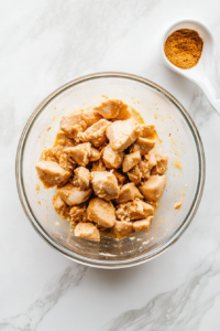 This image shows diced chicken being mixed with marinade ingredients