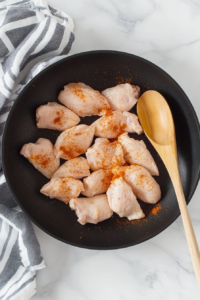 This image shows chicken breasts sizzling in the skillet as they cook.