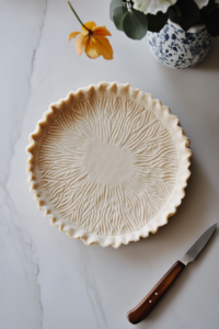 This image shows rolled-out dough being carefully placed and adjusted into a pie tin, forming the base for the vegan lemon meringue pie.
