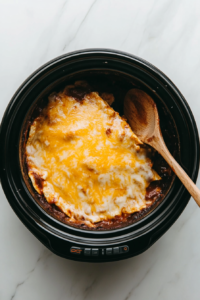 This image shows the fully cooked Crockpot Enchiladas in the slow cooker, with melted cheese and bubbling sauce.