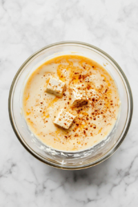 This image shows tofu strips being soaked in a vibrant and aromatic marinade to absorb rich flavors.