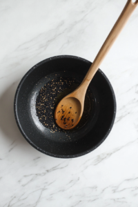 This image shows mustard seeds sizzling in hot oil, releasing their nutty aroma and adding depth to the flavor of the Goan Fish Curry.