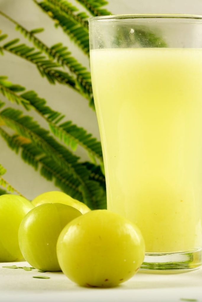 vibrant-green-amla-juice-in-a-glass-surrounded-by-fresh-gooseberries