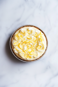 finished-no-bake-lemon-cheesecake-decorated-with-piped-cream-lemon-slices-and-fresh-zest-on-top