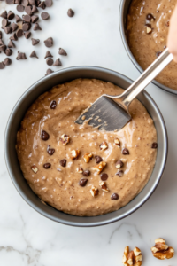 This image shows cake batter being evenly poured into greased round pans, ready to be baked to golden perfection.