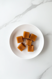 This image shows soft caramels sliced into neat squares and arranged on a clean white marble countertop.