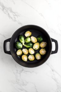 sauteing-garlic-and-brussels-sprouts-in-black-dutch-oven-over-white-marble-cooktop